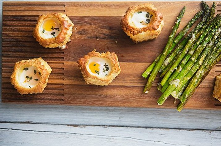 Four parmesan and thyme pastry baked eggs with a side of asparagus.
