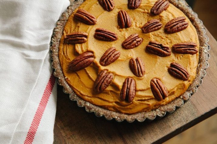 A healthy, no-bake pumpkin pie decorated with whole pecans.
