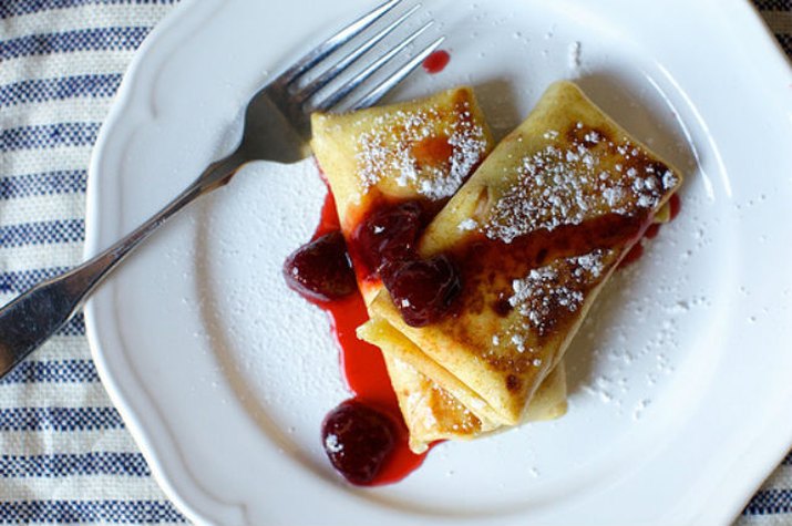 Two cheese blintzes topped with powdered sugar and strawberry compote