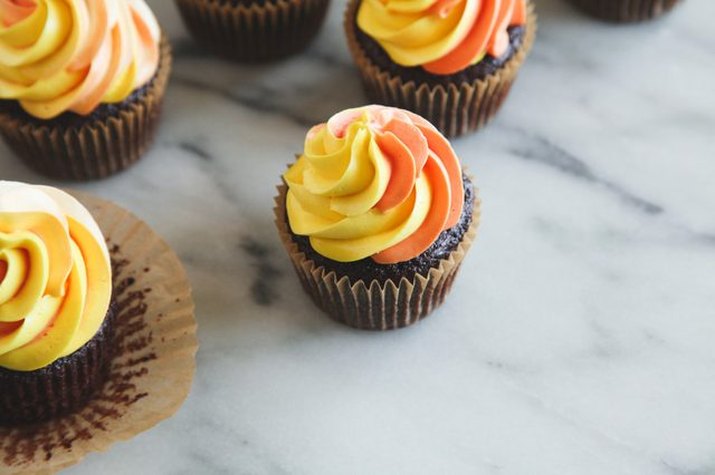 Chocolate cupcakes with yellow and orange frosting.