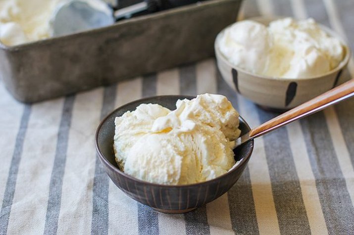 Two bowls of vanilla ice cream on a stripped table cloth