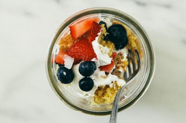 A mason jar filled with lemon cake, coconut cream and fresh berries.