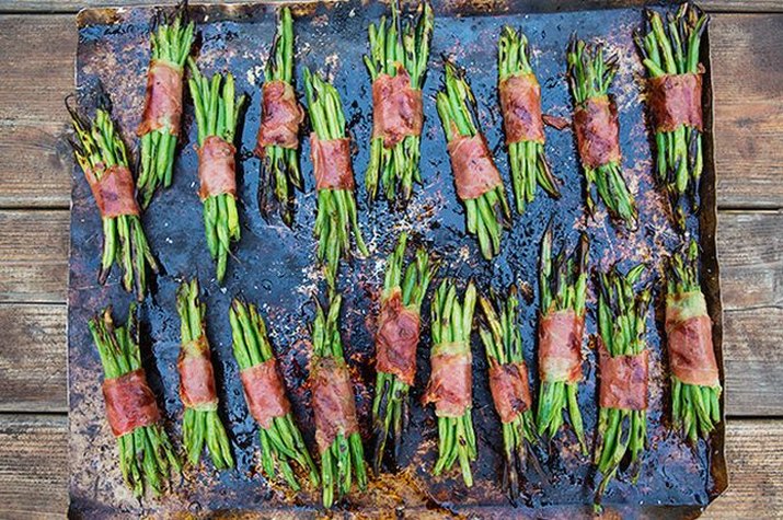 Many just-grilled crisped prosciutto green bean bundles.