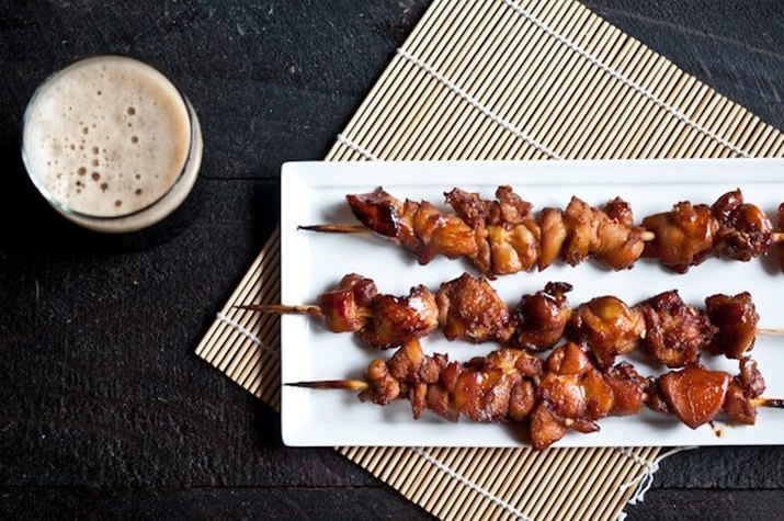 Three chicken skewers served with a porter.