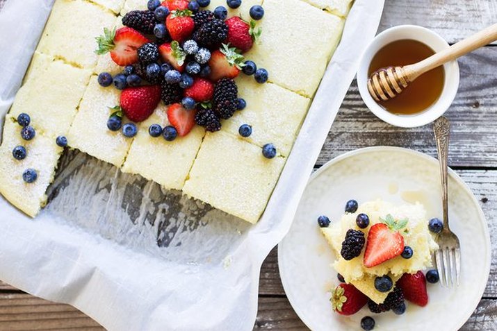 Sheet pan pancakes served with honey and fresh berries
