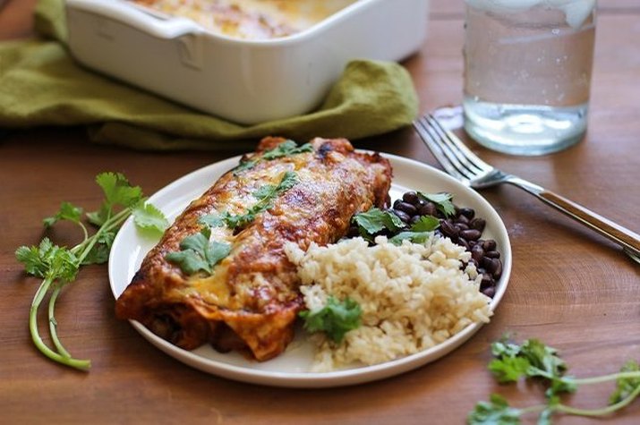 A plate of vegetarian enchiladas, black beans and brown rice.