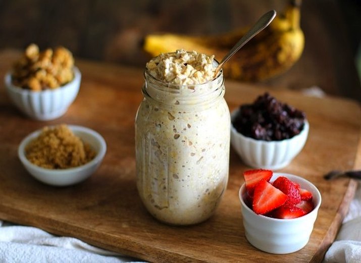 Mason jar of overnight oatmeal next to mini containers of fruit toppings.