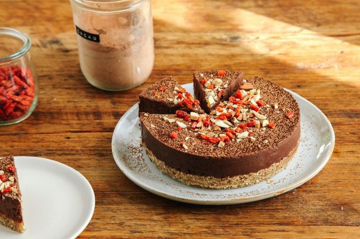 A sliced chocolate and almond tart sprinkled with almond slices and goji berries.