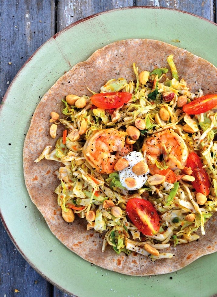 Plate with shrimp fajitas and honey-roasted peanuts on a tortilla.