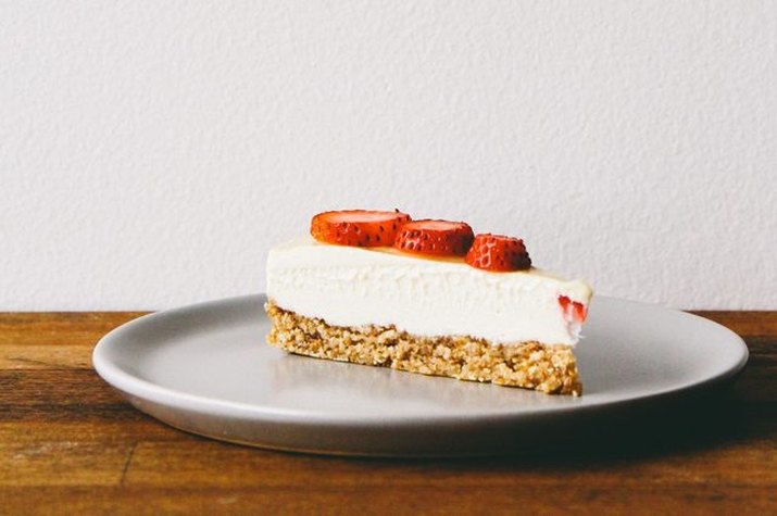 A slice of vegan cheesecake with sliced strawberries on top.