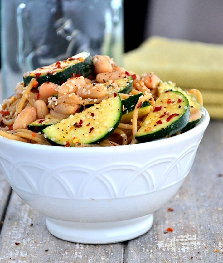 A hearty bowl of spicy white bean and zucchini spaghetti with sesame seeds and red pepper flakes.