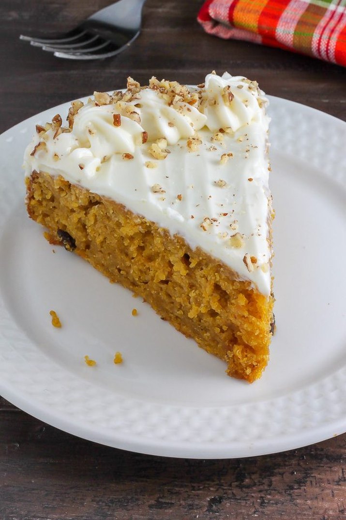 A spongy, orange pumpkin cake topped with cream cheese frosting and sprinkled with nuts.