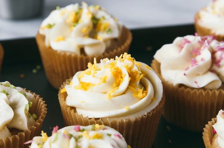 Vanilla cupcakes decorated with frosting and colorful coconut sprinkles.