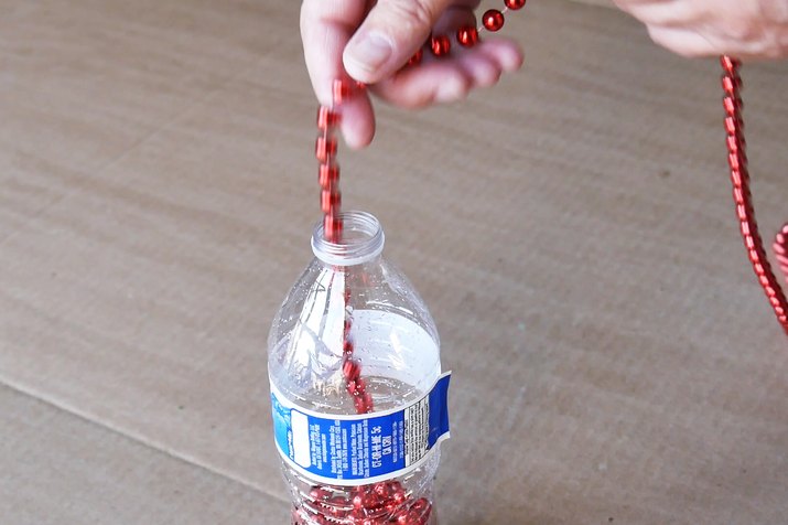 Bead garland being placed in water bottle