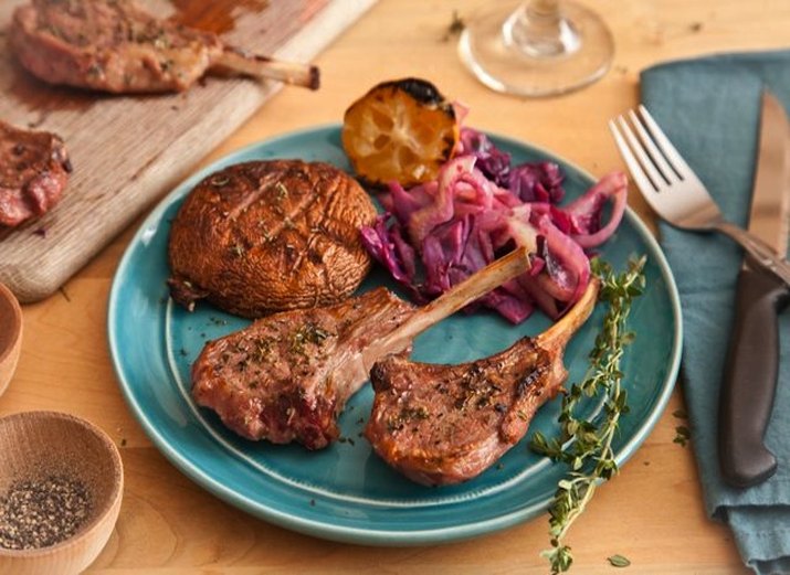 Plate of grilled lamb chops with grilled mushroom cap, orange, and red cabbage coleslaw.