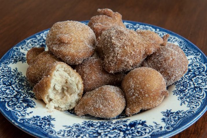 Deep-fried homemade doughnuts sprinkled with cinnamon and sugar.