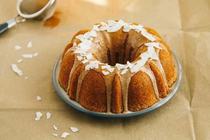 A bright orange coconut-pecan carrot cake with cinnamon glaze and coconut flakes.