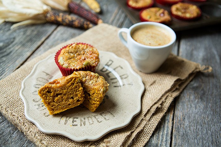 Pumpkin muffins on a plate next to a cup of coffee.