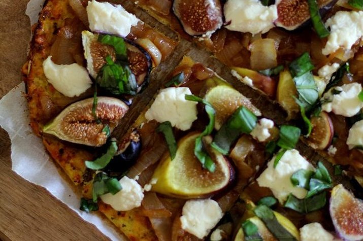 A cauliflower-crusted pizza topped with basil, figs and cheese.