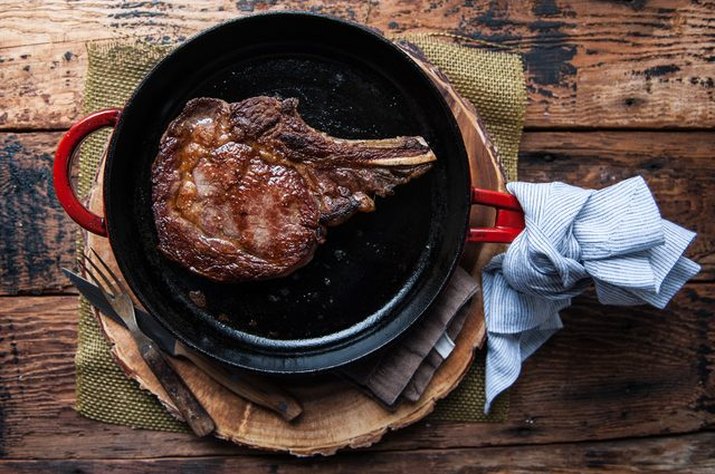 a red cast iron skillet with a perfectly seared steak