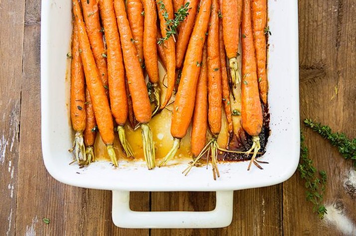 A white casserole dish with roasted honey-rum glazed carrots