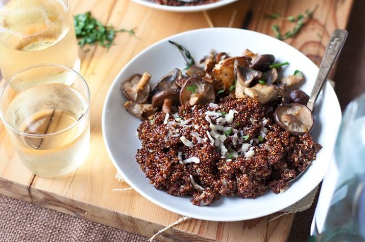 A bowl of wild mushroom quinoa risotto served with wine.
