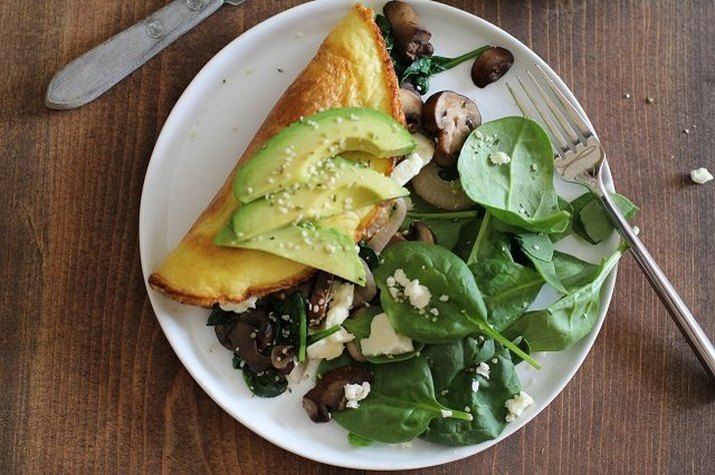 An omelet served with avocados and spinach salad.