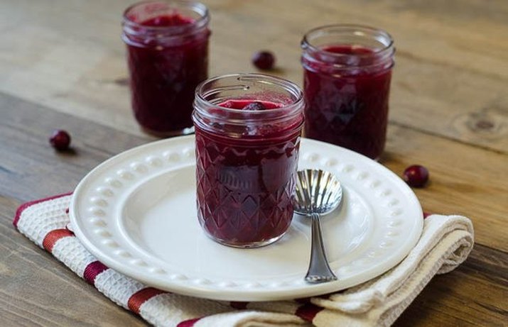 Small mason jars filled with sweet and tangy cranberry sauce.