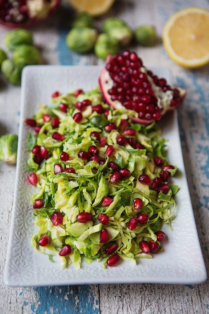 A colorful plate of Brussels sprouts sprinkled with pomegranate arils.